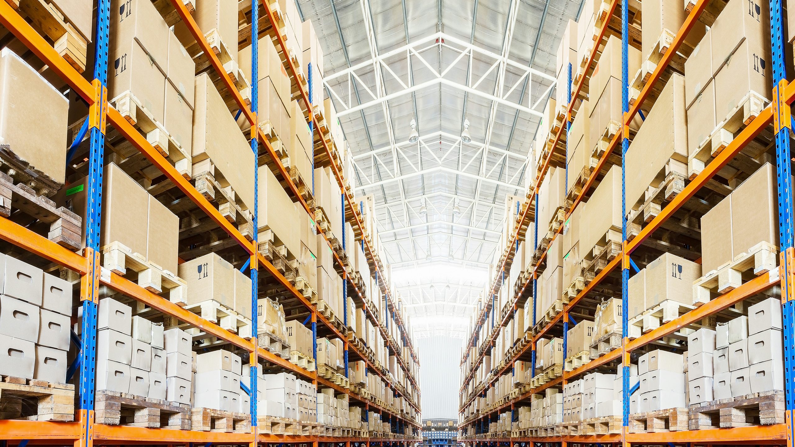 The image shows a warehouse with a modern automated storage and retrieval system (AS/RS) in operation.