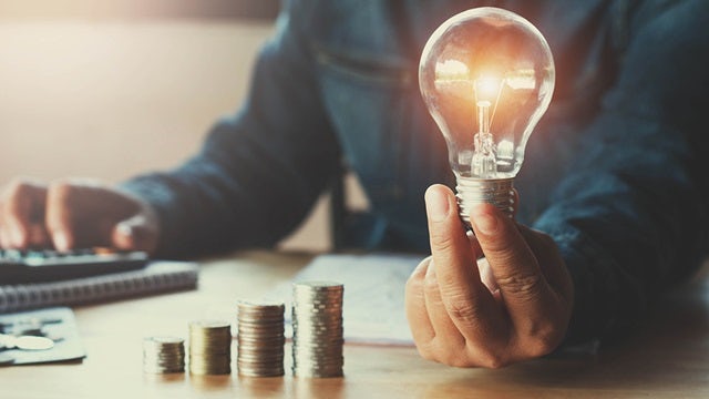 Person holding magnifying glass over financial newspaper with stock market data and charts