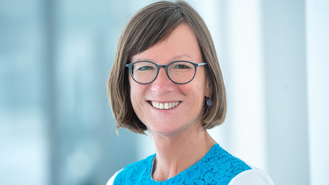 Professional businesswoman in formal attire looking confidently at the camera in an office setting.