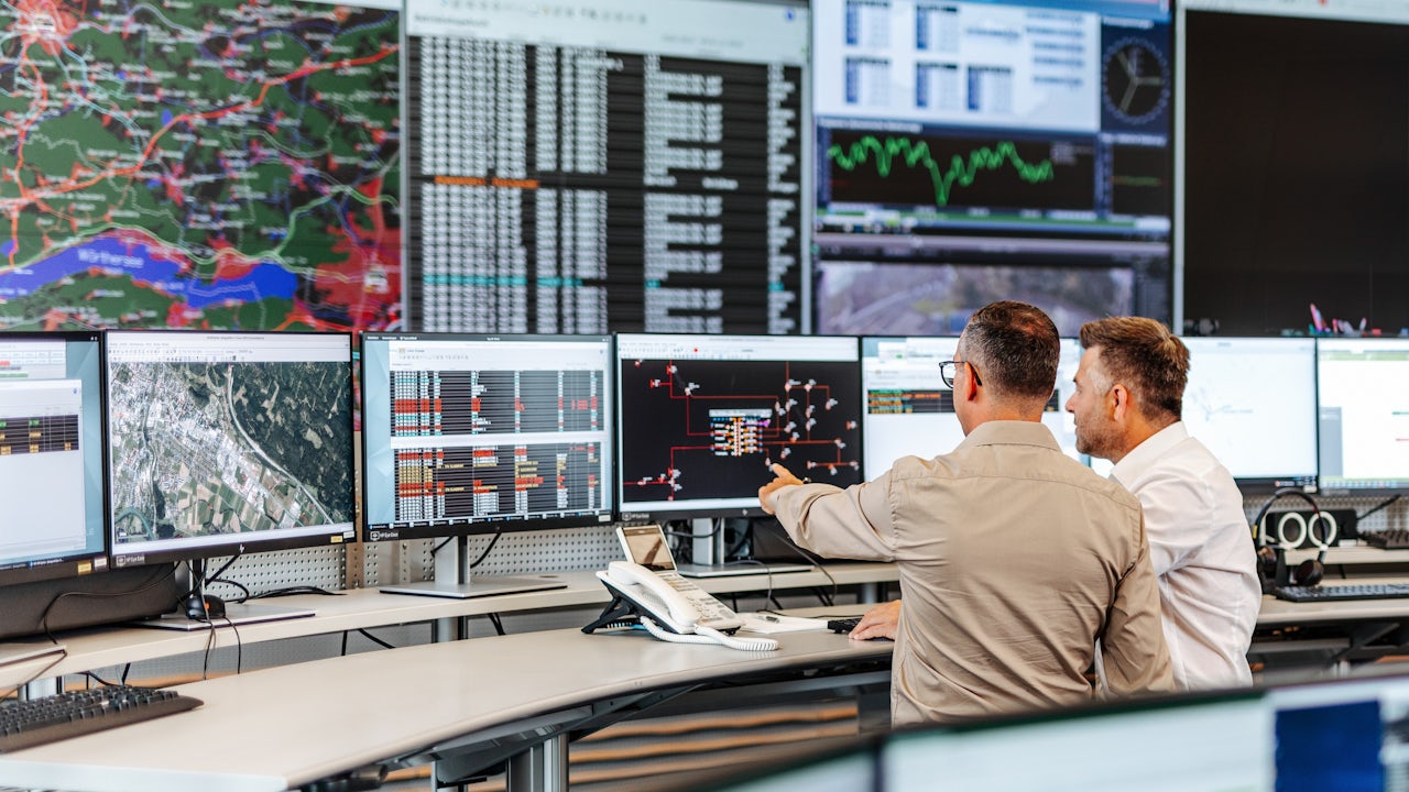 Grid operators reviewing a wall of display screens.
