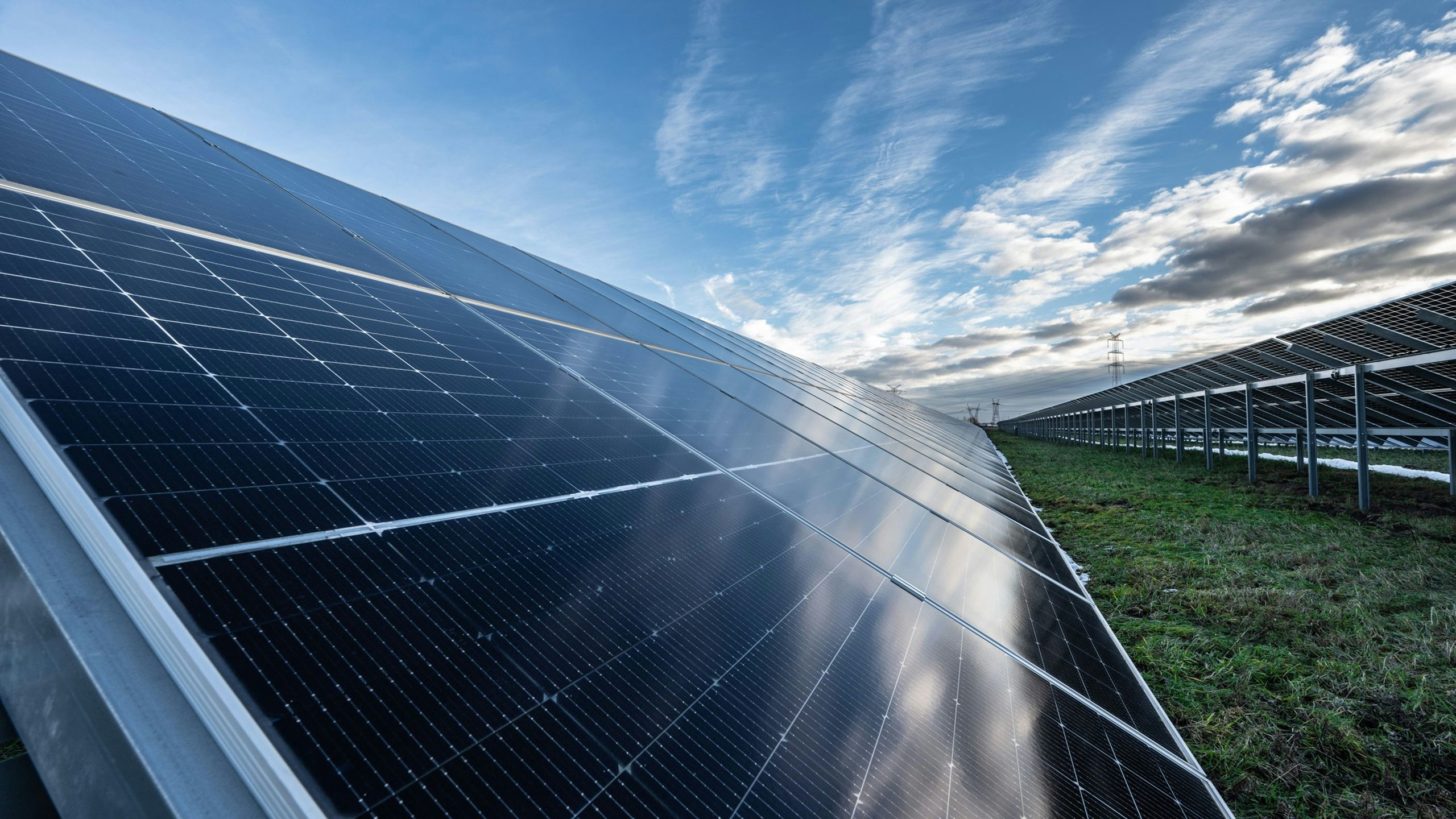A solar panel farm with multiple rows of solar panels under a clear blue sky.