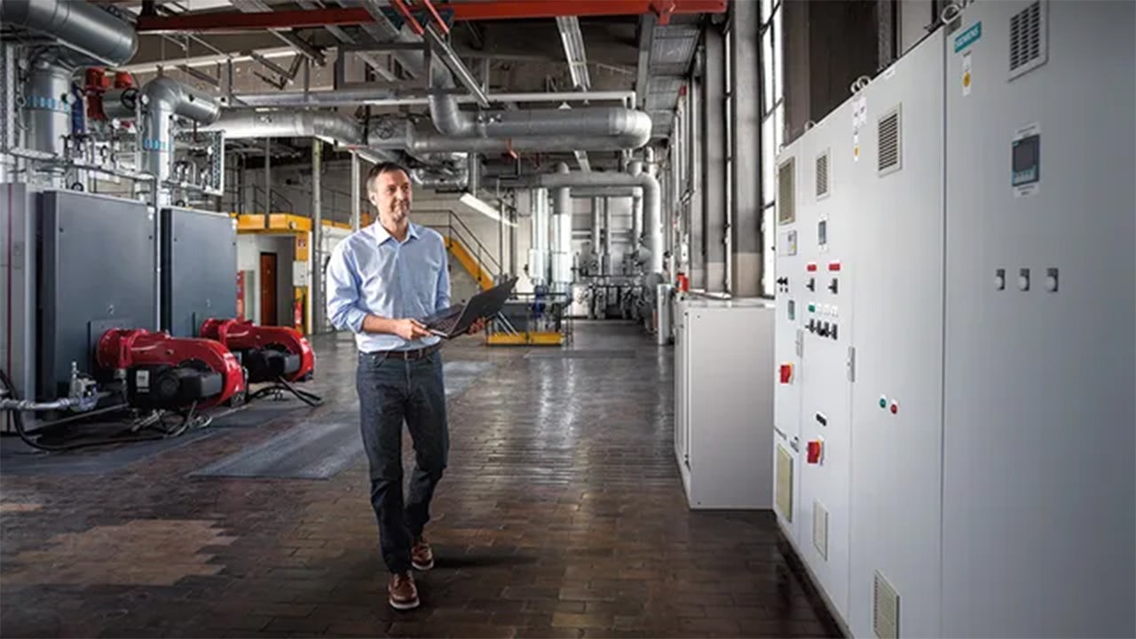 Man walking with laptop in hand.