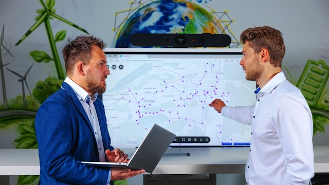 Two people stand in front of a large screen showing Gridscale X LV Insights. 