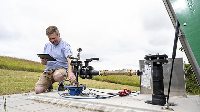 Man tests waterworks equipment while looking at a tablet