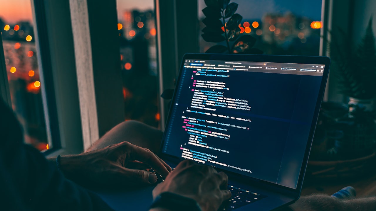 A software developer is working on a laptop with a cybersecurity software development project.