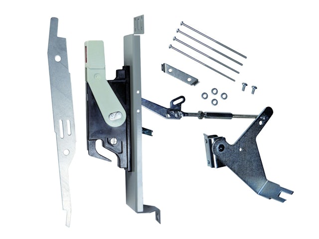 A man is working on a car engine in a garage, with tools and parts scattered around him.