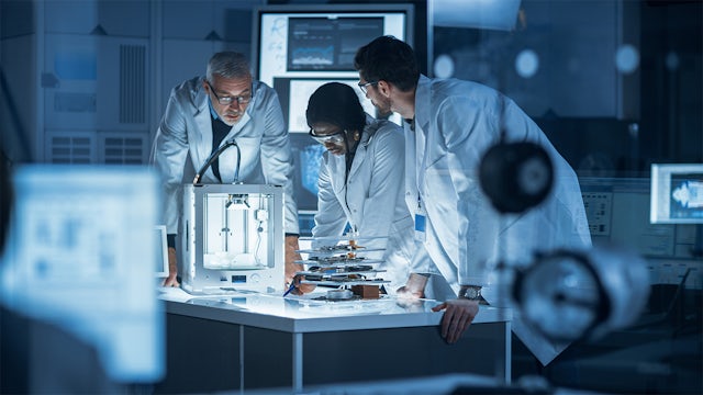 Three medical device engineers review 3D-printed prototypes.