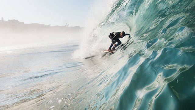 Adult man surfing a rolling wave in Leucadia, California.