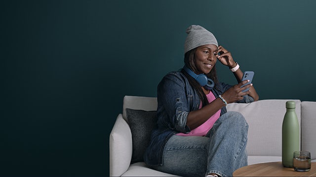 A person is working on a laptop while sitting on a couch in a living room.