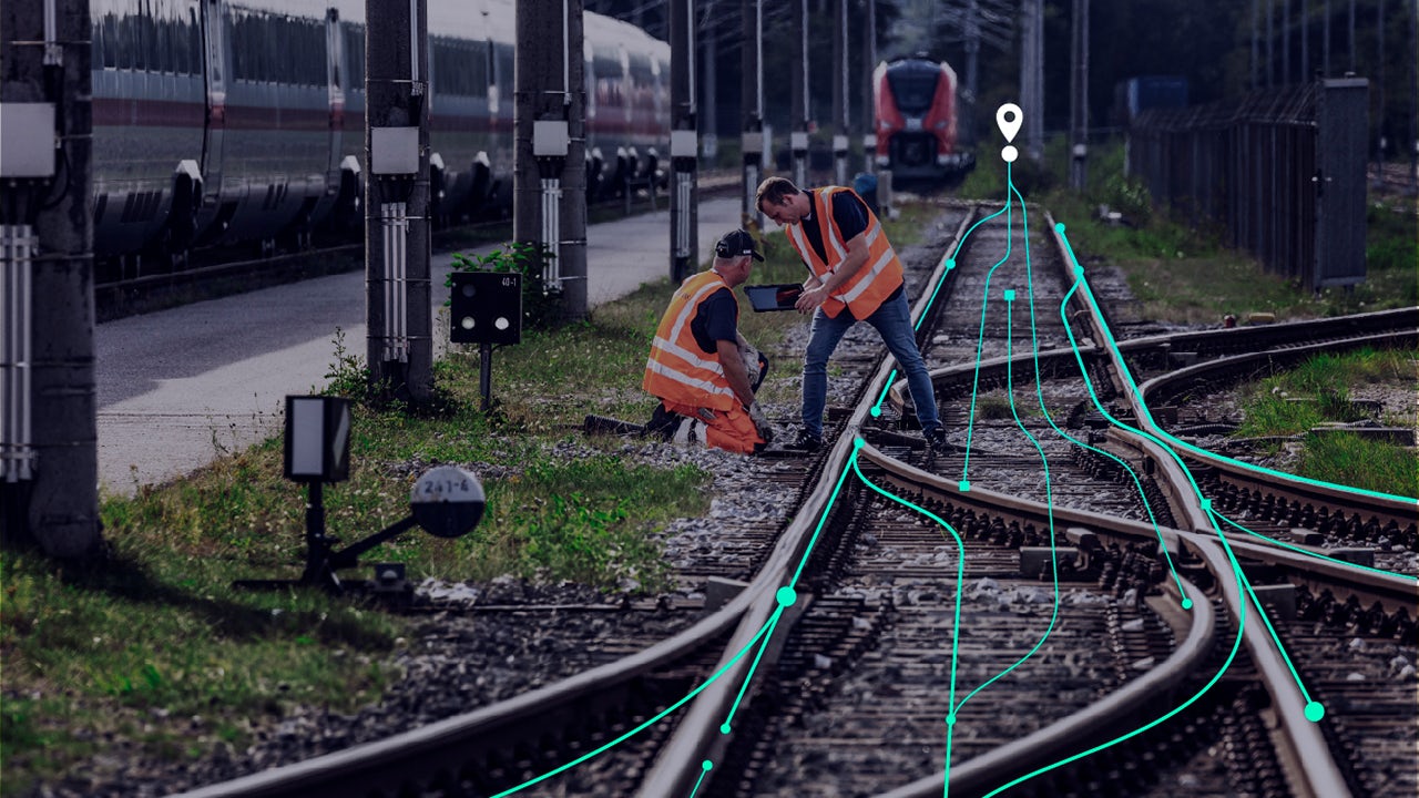 A person is standing in front of a white wall with a blue and white logo on it.