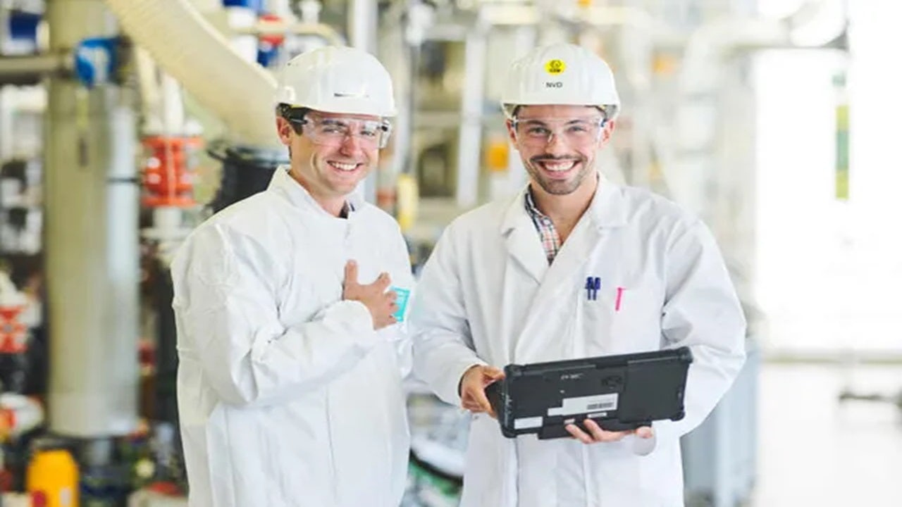 Two smiling technicians in a modern industrial facility