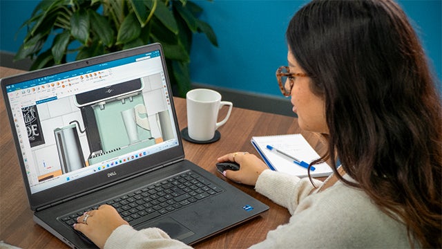 A woman sits at a laptop, looking at a dashboard in NX