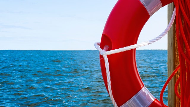 Orange life preserver ring floating on blue ocean water