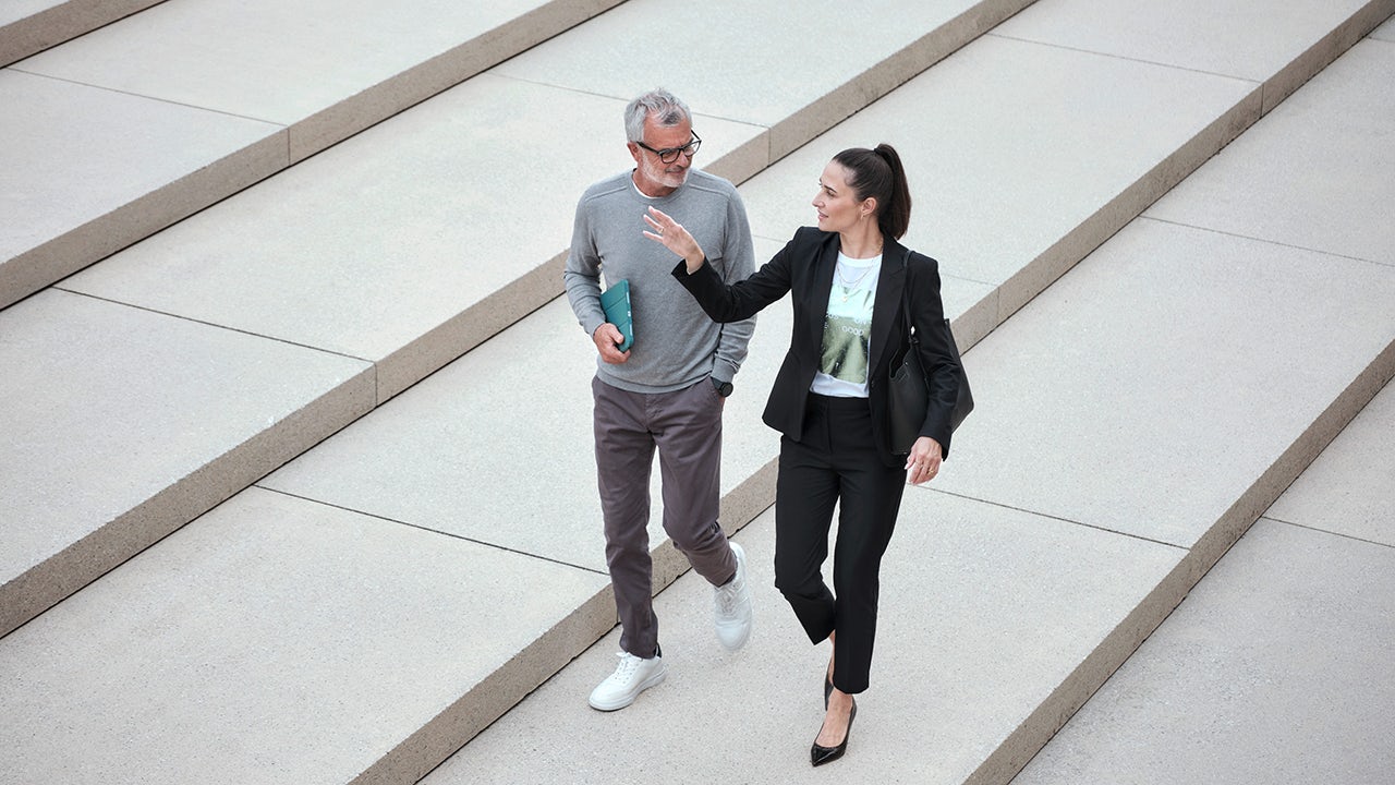 A person wearing a mask and gloves standing in front of a blue wall with a white sign.
