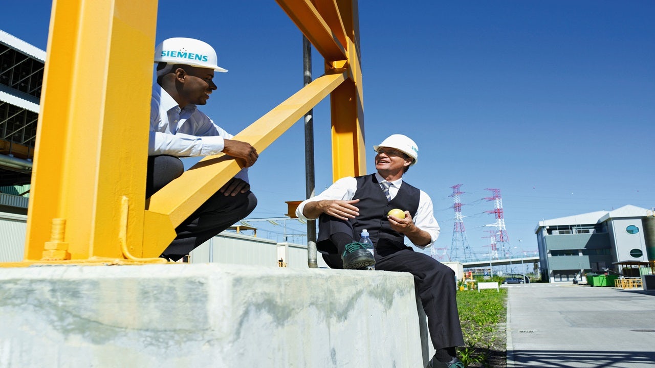 People in Siemens branded hard hats at a job site.
