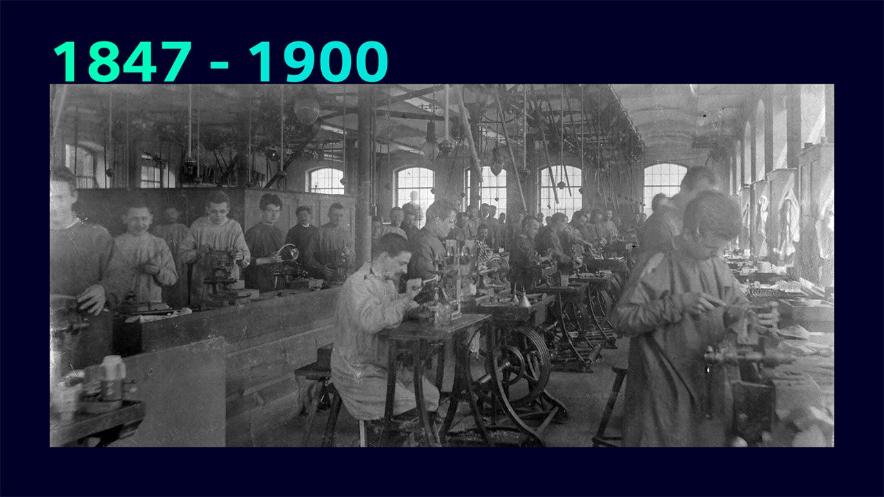 A person is standing in front of a large screen displaying financial data and graphs.