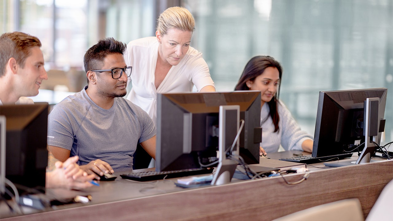 Engineers at the office working and their manager is supervising them. 
