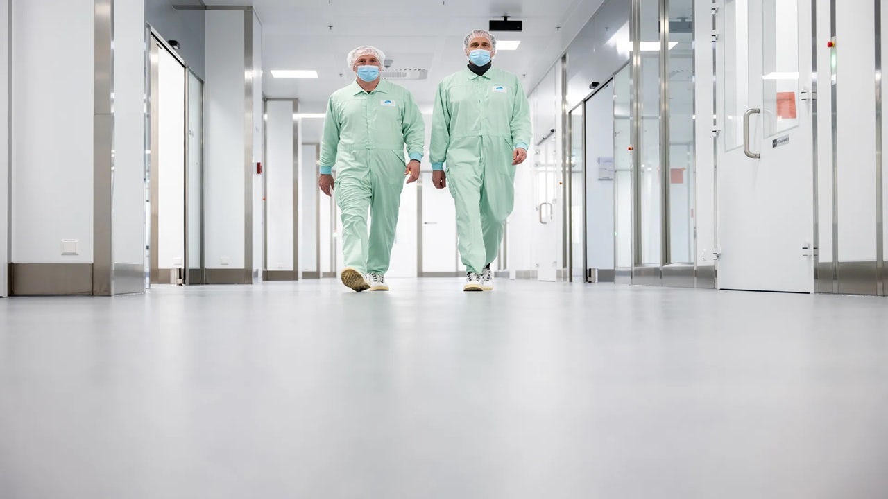 Two people in protective clothing walking forward.