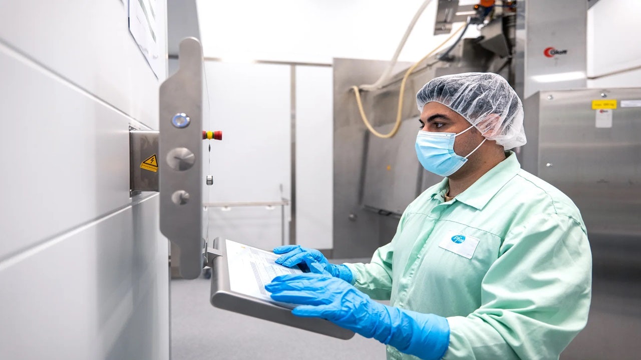 Person in a mask and gloves working on a computer.