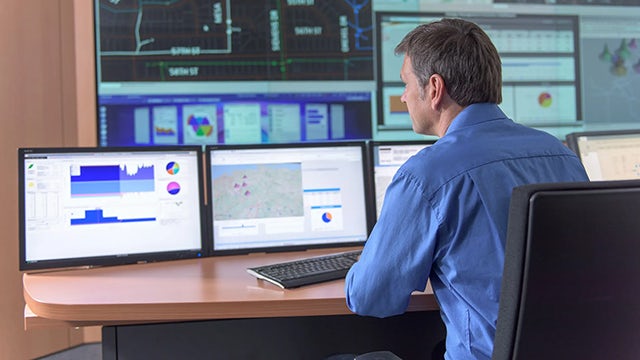 Man sitting in front of computer monitors.