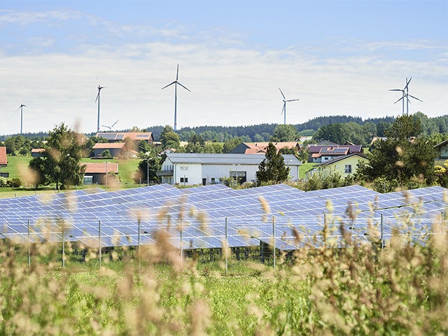 Modern cityscape with sleek skyscrapers and power grid infrastructure against a bright blue sky backdrop.