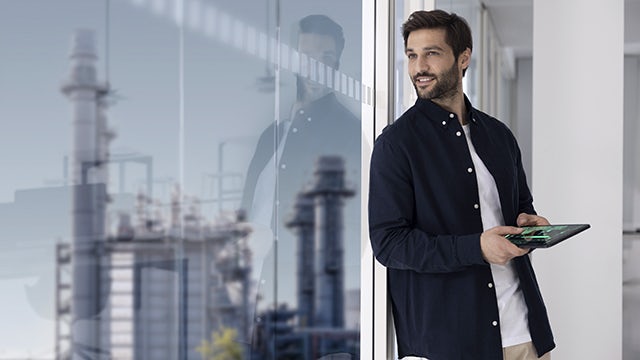 Man holding tablet device while looking out the window.