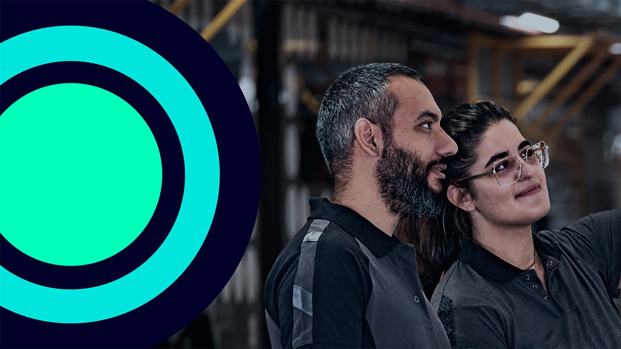 Wind turbines on a grassy hill against a blue sky with white clouds.