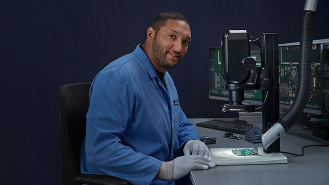 A person is sitting on a chair and appears to be working on a laptop.