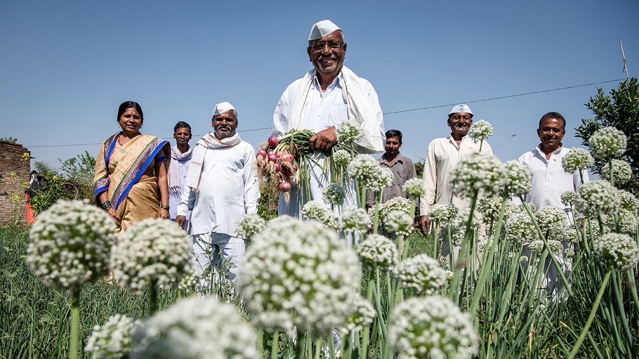 A person is standing in front of a building with a banner that reads 