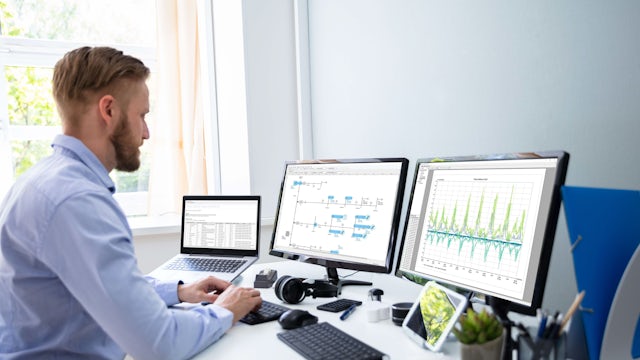 A Siemens multi-monitor setup and an engineer running PSS®SINCAL simulation software on multiple monitors