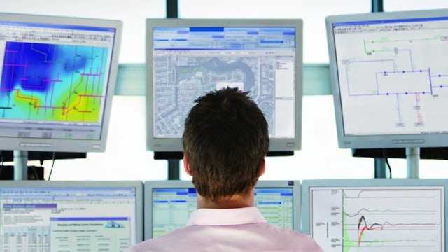 Man running power system simulation and modeling software on multiple stacked monitors