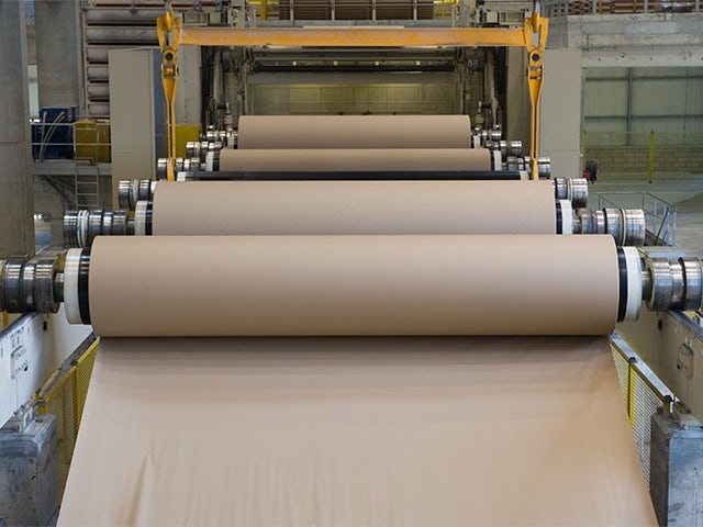 A factory with a large building and a machinery vehicle in front of it.