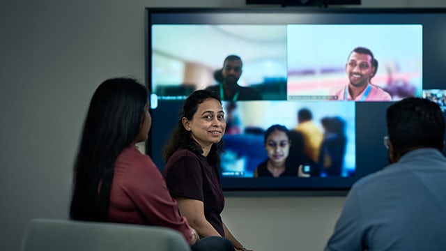 The image shows a person standing in front of a large screen with a motivational quote displayed.