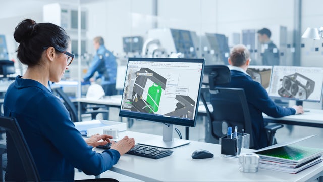 Woman working on a part model in Solid Edge from a desk workstation in an office environment