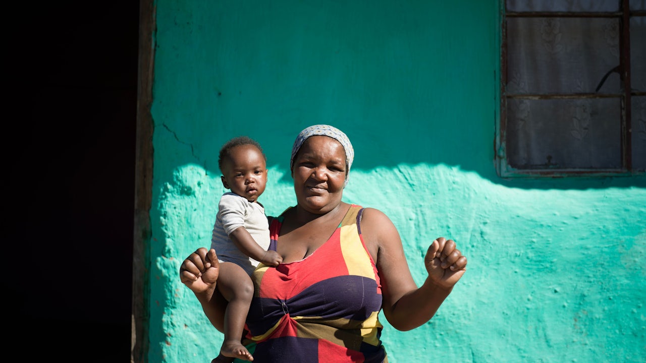 Happy South African woman posing with baby in rural village.