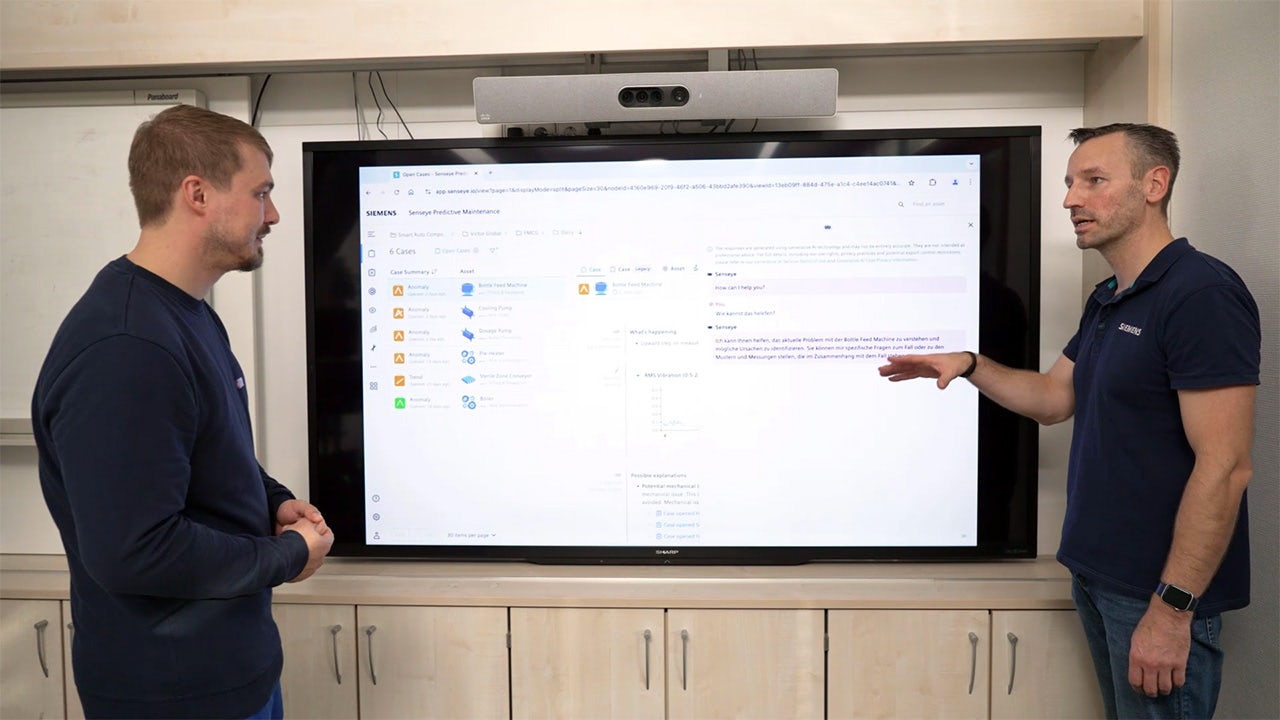 Two engineers discussing the results from the Senseye Predictive Maintenance application on a large screen.