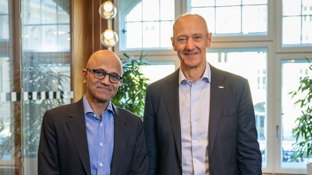 A person is standing in front of a building with a Siemens logo on the wall. 