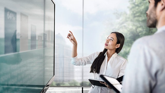 A person is standing in front of a large screen displaying a visual feature with a blue background and white text.