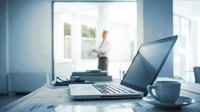 A group in formal wear poses in front of a modern building with a "Poland" sign on a sunny day.