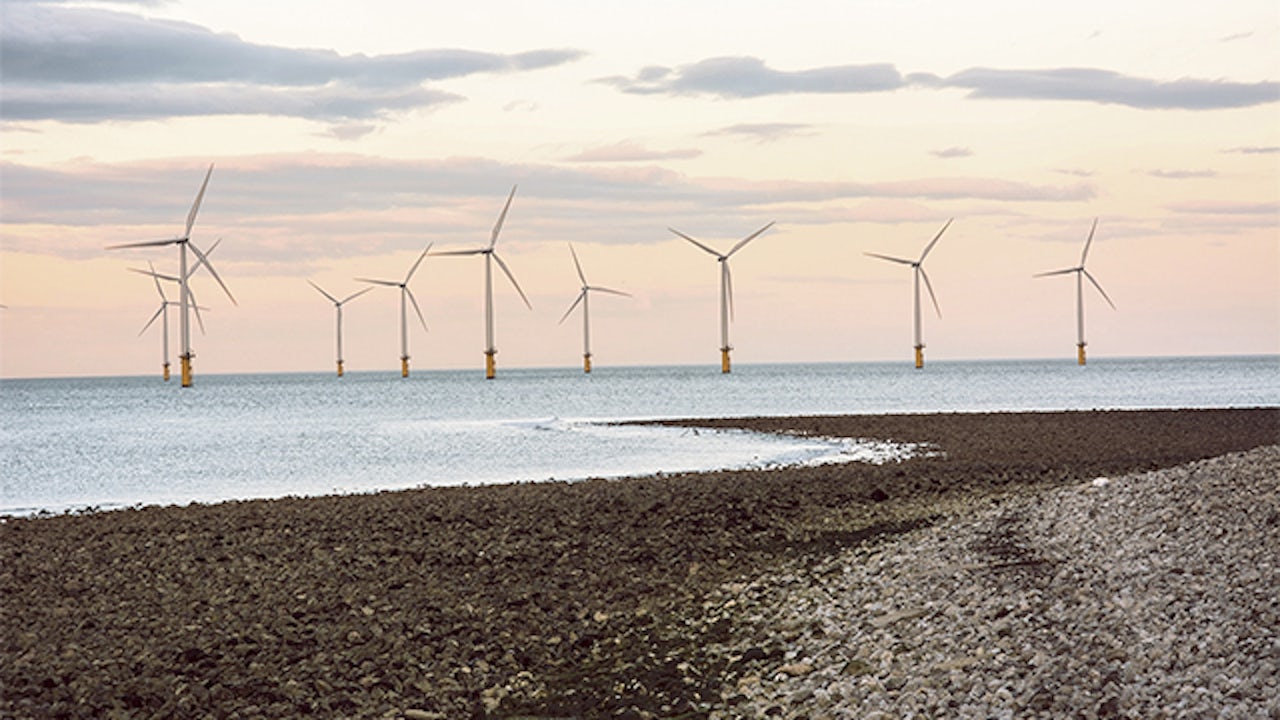 A beach with a wind farm in the background.