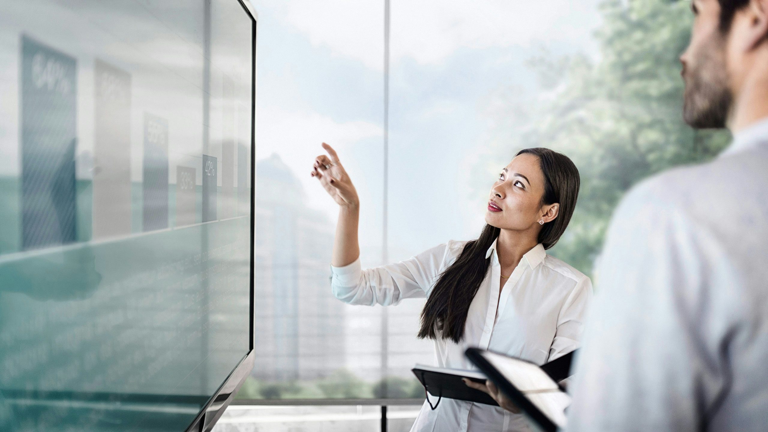 A person stands before a vibrant screen with abstract geometric shapes in bold, dynamic colors.