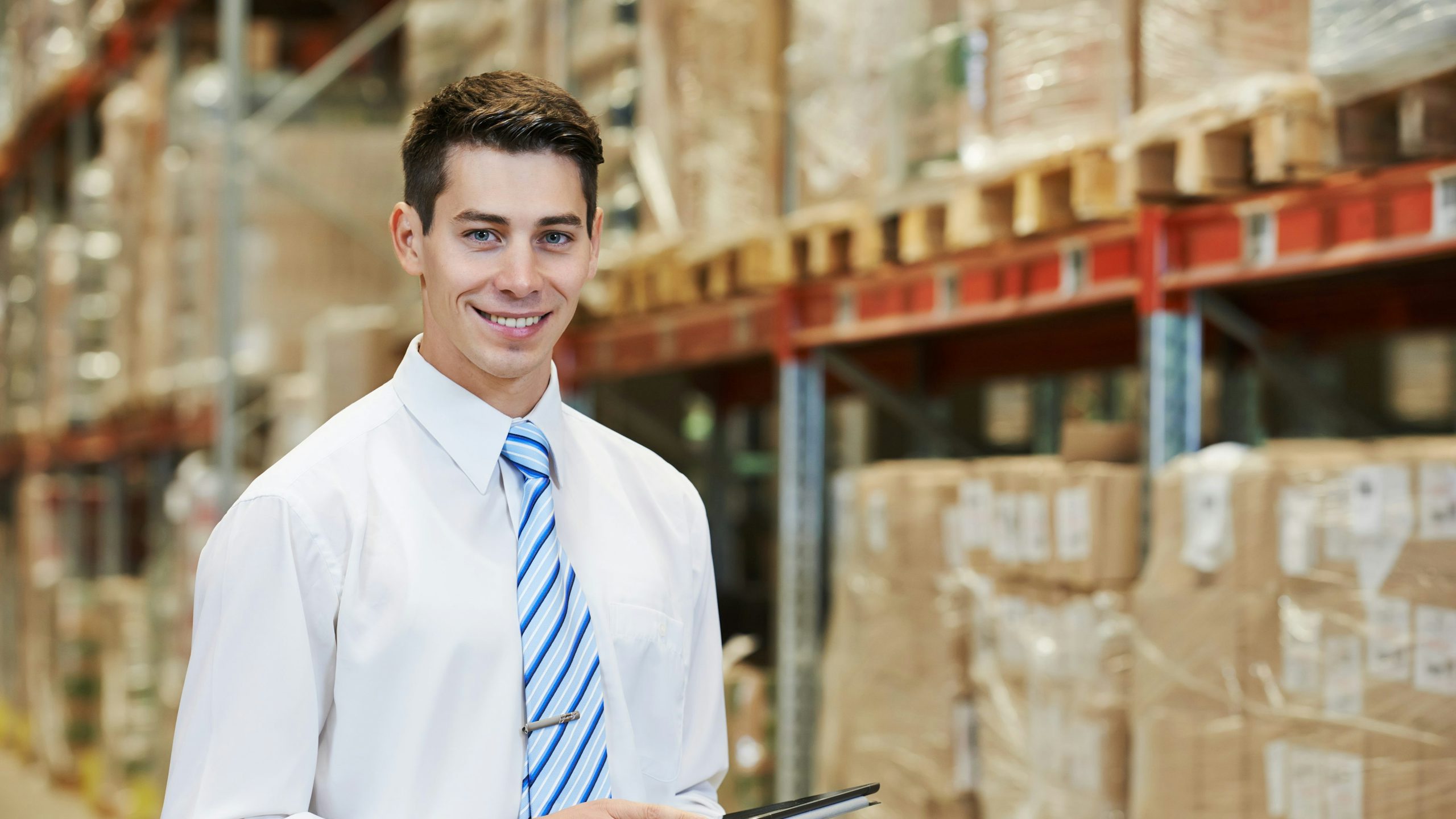 A manager using a tablet on a warehouse
