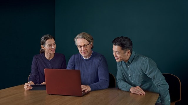 Group of people around an open laptop.