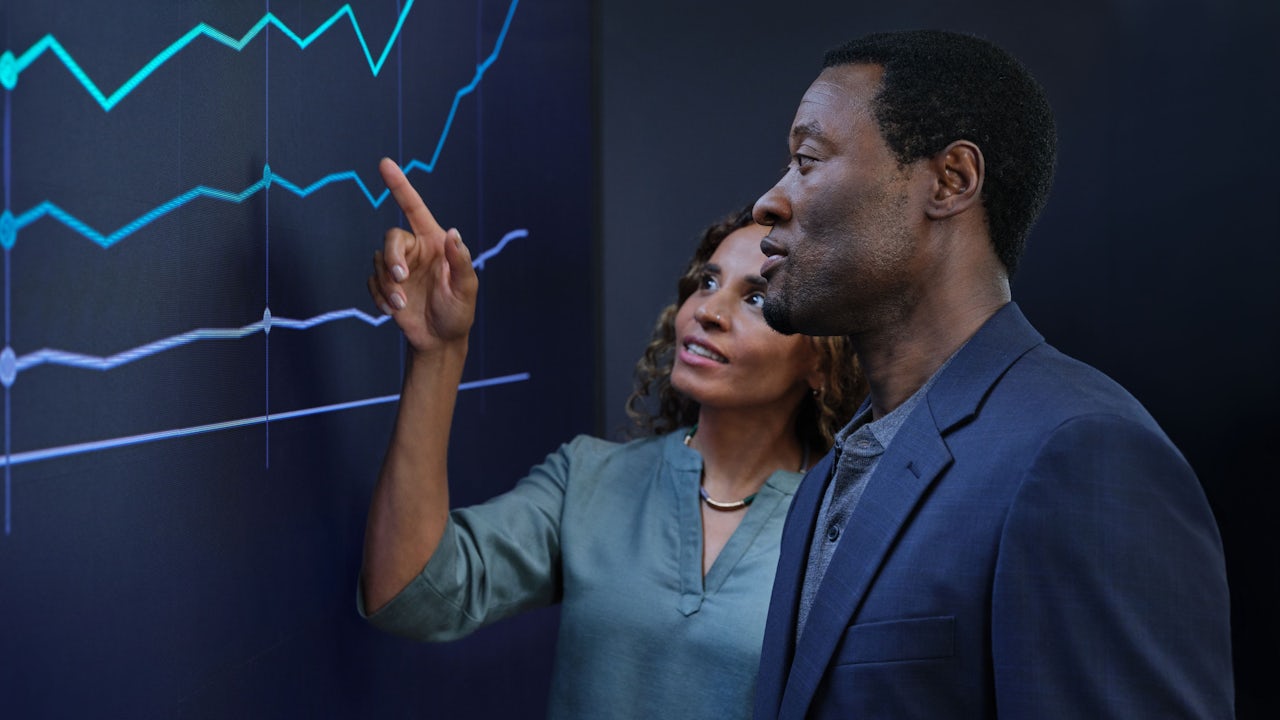 Two people analyzing data on a graph.