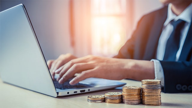 Businessman working with coin money currency next to a laptop.
