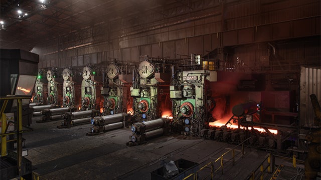 Siemens Aperam case study feature image showing a factory with workers and machinery.