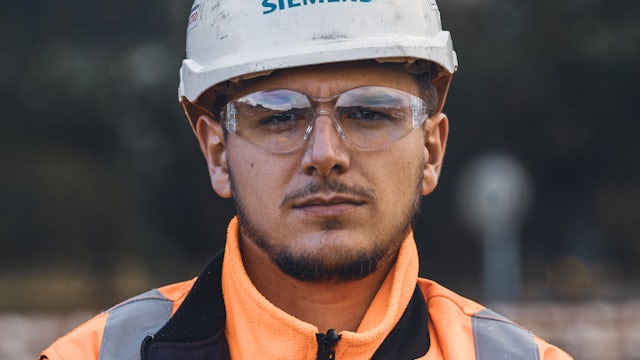 A man standing with his arms crossed, wearing safety gear