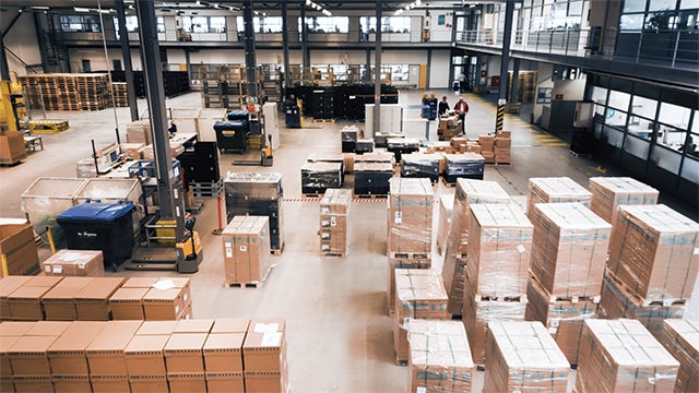 A modern distribution center with a large warehouse and a modern building in the background.