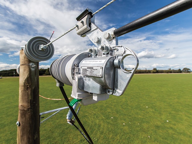 Cylindrical blue device with metal connectors mounted on electrical pole