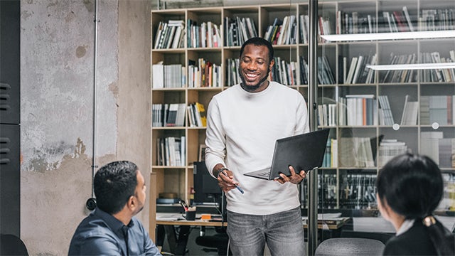 Professional businessman standing confidently outside modern corporate office building with glass facade.
